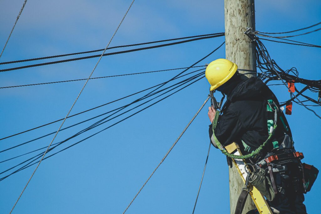Utility worker climbing electrical pole for maintenance